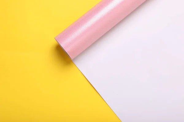 stock image Roll of pink wrapping paper on yellow background, top view. Space for text