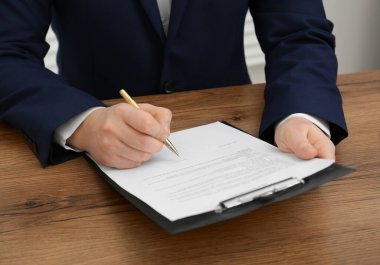 Ahşap masada belge imzalayan adam, yakın plan