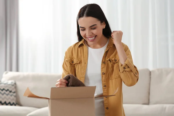 感情的な若い女性の自宅で小包を開く インターネットショッピング — ストック写真