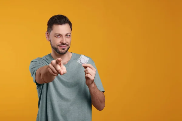 Handsome Man Holding Condom Orange Background Space Text — Stock Photo, Image