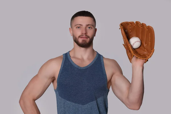 ライトグレーの背景に手袋と野球ボールを持つアスレチック若い男 — ストック写真