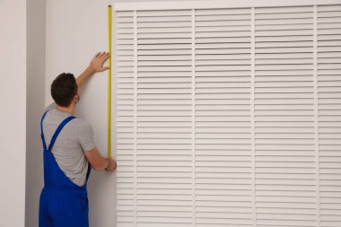 İçeriye yatay pencereler kurarken mezura kullanan üniformalı işçiler