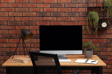 Evdeki masasında bilgisayar ve lamba olan rahat bir iş yeri.