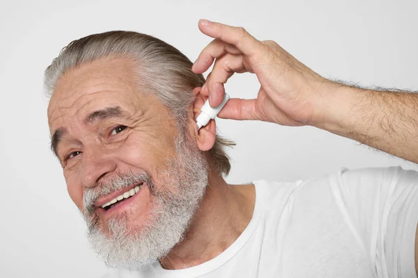 老年人在白色背景上使用滴耳剂 — 图库照片