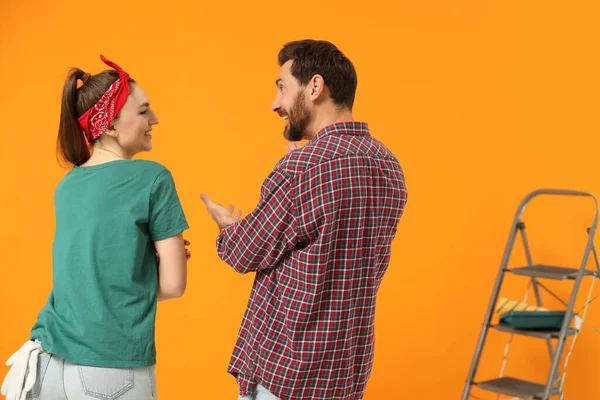 Szczęśliwi Projektanci Rozmawiający Przy Świeżo Pomalowanej Pomarańczowej Ścianie Widok Tyłu — Zdjęcie stockowe