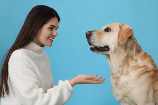 快乐女人与可爱的拉布拉多猎犬检索浅蓝色背景 — 图库照片