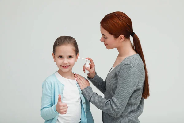 Mother Spraying Medication Daughter Ear Light Grey Background — Stock Photo, Image