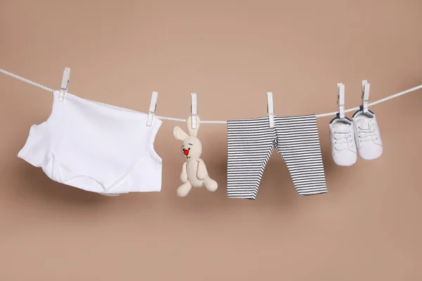 茶色の背景に洗濯ラインにかかってかわいい小さな赤ちゃんの靴 服やおもちゃ — ストック写真