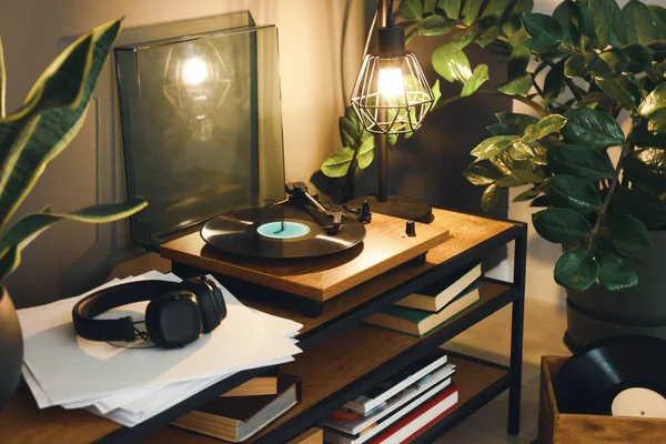 Stylish turntable with vinyl record on table in cozy room