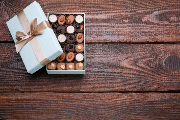 Open box of delicious chocolate candies on wooden table, top view. Space for text