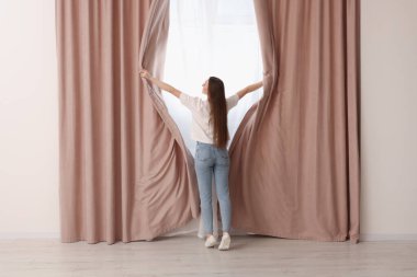 Kadın evde şık perdeler açıyor, arka manzara...