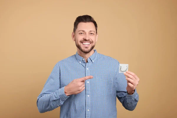 Happy Man Holding Condom Beige Background Closeup — Stock Photo, Image