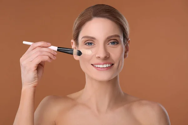 Woman Applying Foundation Face Brush Brown Background — Stock Photo, Image