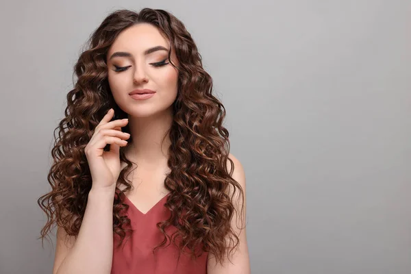 長い巻き毛の茶色の髪を持つ美しい若い女性灰色の背景 テキストのためのスペース — ストック写真