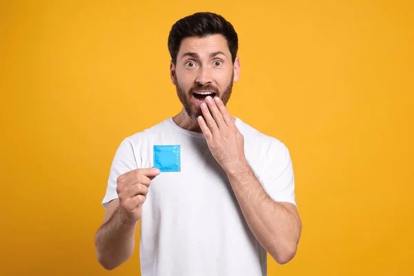 Homem Emocional Segurando Preservativo Fundo Amarelo Sexo Seguro — Fotografia de Stock
