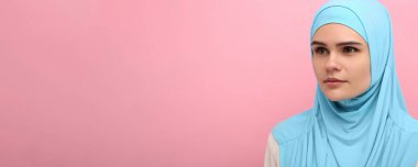 Pembe arka planda tesettürlü Müslüman kadın portresi, mesaj için boşluk. Pankart tasarımı