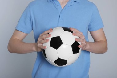 Açık gri arka planda futbol topu olan çocuk, yakın plan.