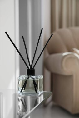 Aromatic reed air freshener on table indoors, space for text