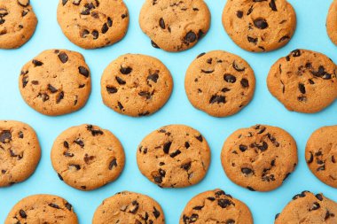 Açık mavi arka planda bir sürü çikolata parçacıklı kurabiye, düz uzanmış.