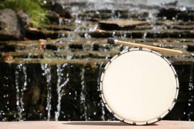 Güneşli bir günde şelalenin yanında davul ve açık hava, mesaj için yer. Perküsyon müzik aleti