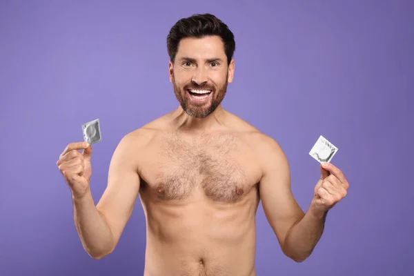 紫色の背景にコンドームを持つ感情的な裸の男 安全なセックス — ストック写真