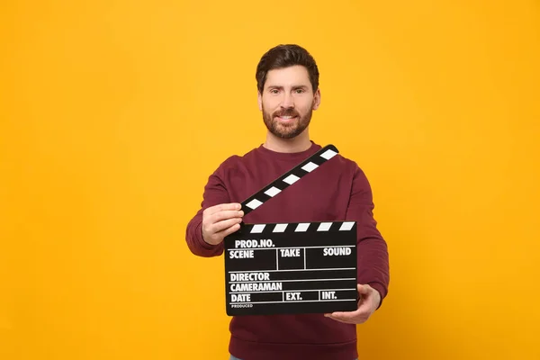 Lächelnder Schauspieler Mit Klemmbrett Auf Orangefarbenem Hintergrund Platz Für Text — Stockfoto