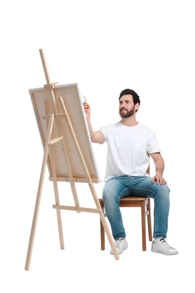 白を背景に筆で絵を描く男 キャンバスを保持するためにイーゼルを使用 — ストック写真