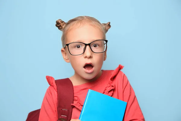 かわいいです女の子とともに眼鏡 バックパックと教科書上のライトブルーの背景 — ストック写真