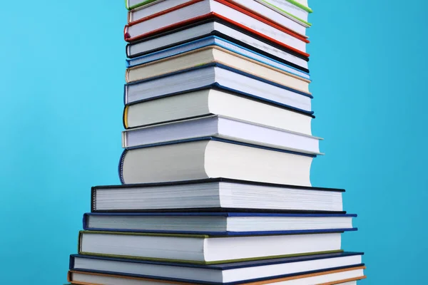 Stack of hardcover books on light blue background, closeup