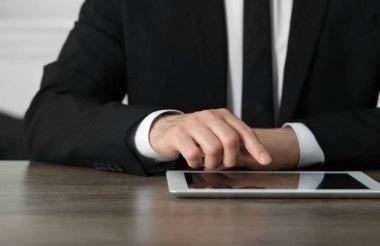 Ahşap masada yeni tablet kullanan bir adamın yakın görüntüsü.