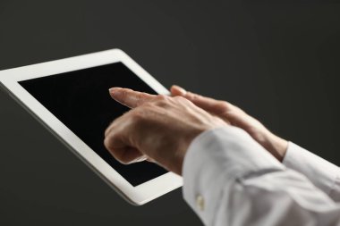 Gri arkaplanda yeni tablet kullanan adamın yakın görüntüsü