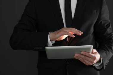 Siyah arkaplanda yeni tablet kullanan işadamının yakın görüntüsü
