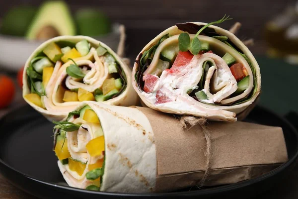 Delicious sandwich wraps with fresh vegetables on plate, closeup