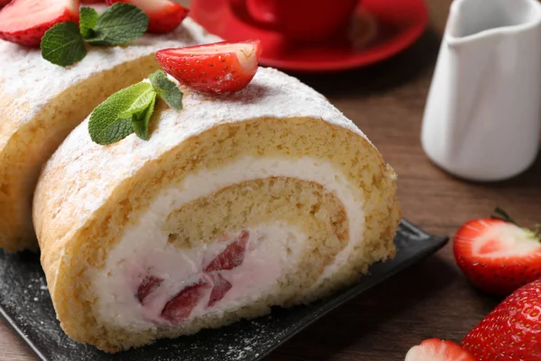 stock image Delicious cake roll with strawberries and cream on black board, closeup