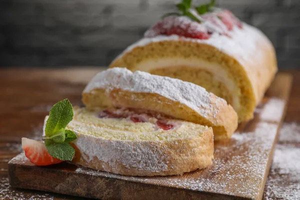 stock image Pieces of delicious cake roll with strawberries and cream on table, closeup