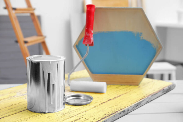 Can of paint and roller on blue wooden table indoors, space for text