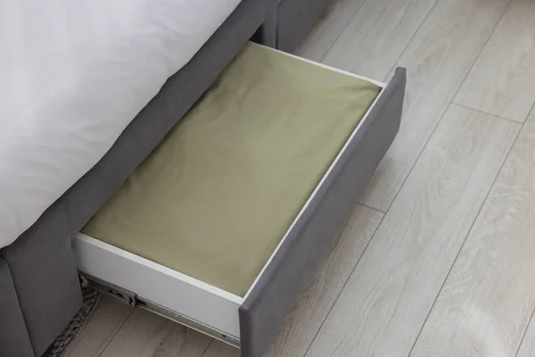 Storage drawer with bedding under comfortable bed in room