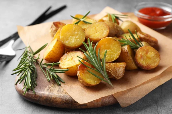 美味的烤土豆和芳香的迷迭香放在木板上 — 图库照片