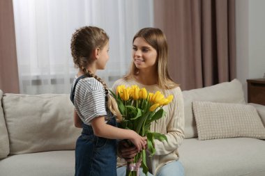 Küçük kızı, annemi evde sarı lalelerle tebrik ediyor. Anneler Günün kutlu olsun.