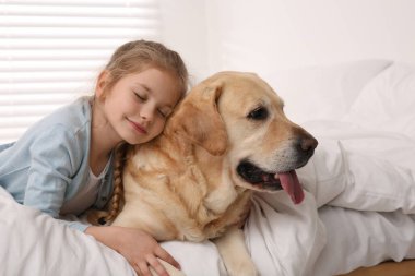 Evde yatakta sevimli köpeğiyle genç bir kız.