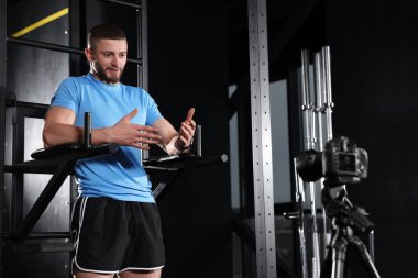Man recording online training on camera at gym. Fitness coach