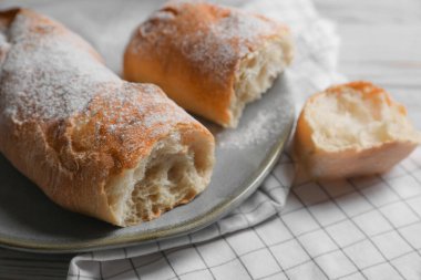 Beyaz ahşap masada taze çıtır ciabatalar, yakın plan.
