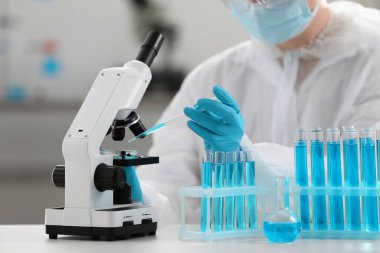 Laboratuvarda mikroskopla çalışırken petri kabına örnek damlatan bilim adamı, yakın plan.