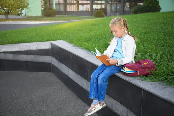 Schattig Klein Meisje Met Een Rugzak Die Schoolboek Leest Straat — Stockfoto