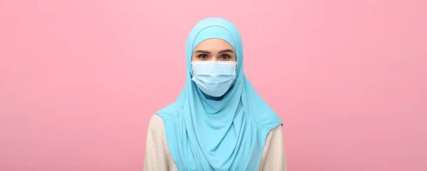 穆斯林妇女的画像 头戴头巾 戴着粉色背景的医疗面具 条幅设计 — 图库照片