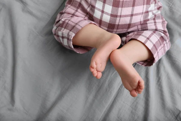 Little baby in pajamas on bed, top view. Space for text