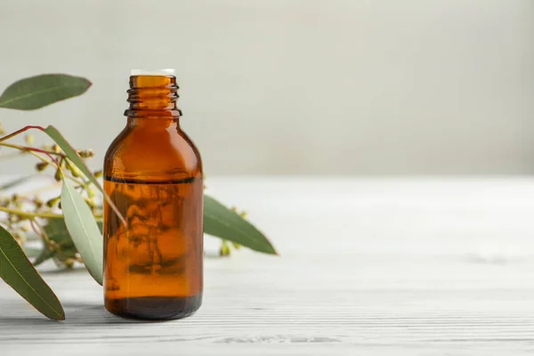 Eine Flasche Ätherisches Eukalyptusöl Und Blätter Auf Einem Weißen Holztisch — Stockfoto