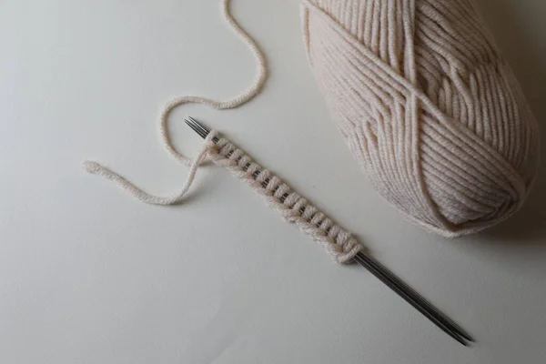 Soft yarn, knitting and metal needles on light background, top view