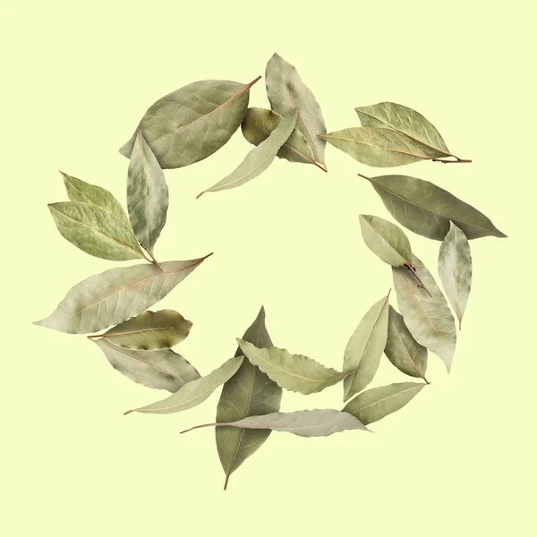 Dry bay leaves falling on pale light yellow background