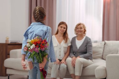 Küçük kız annesini ve büyükannesini çiçeklerle tebrik ediyor. Anneler Günün kutlu olsun.